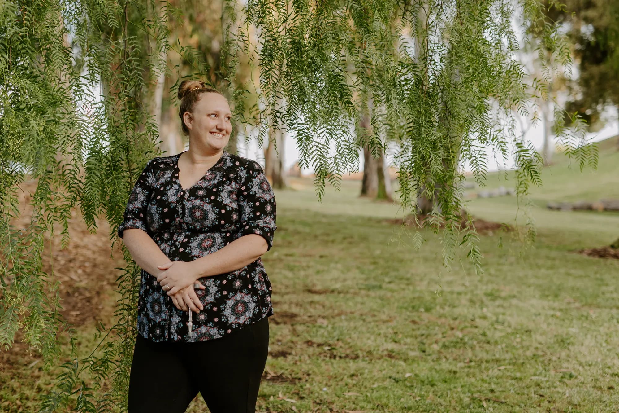 Dr. Caitlin Walker, upper cervical chiropractor in Oceanside, outdoors among willow trees